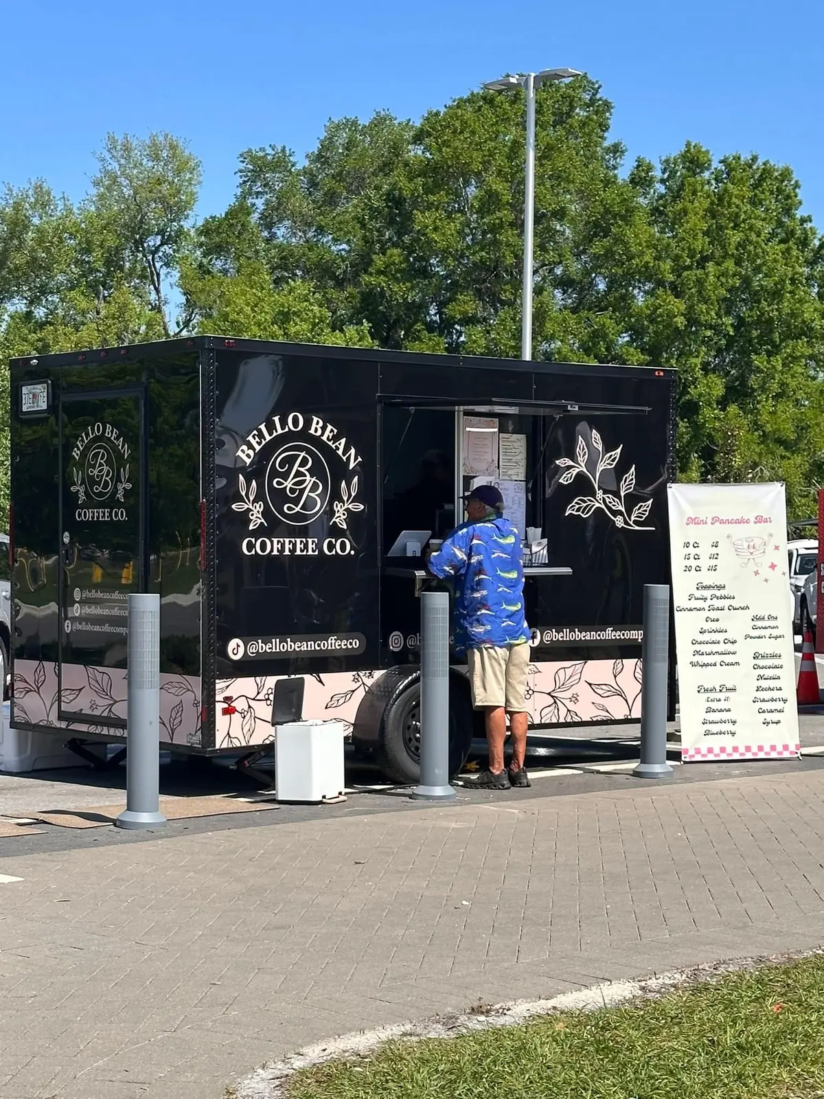 The black and blush Bello Bean Coffee Company truck serving customers outdoors